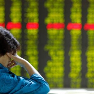 A Chinese investor takes a nap in front of an electronic board showing stock prices at a securities brokerage house in Beijing